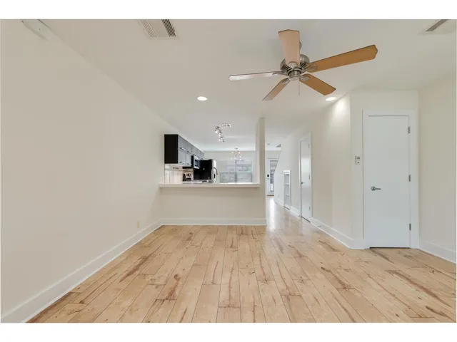 a view of empty room with wooden floor and ceiling fan
