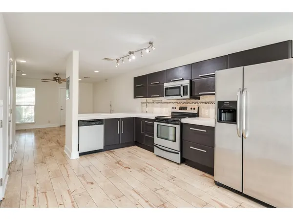 a kitchen with stainless steel appliances kitchen island granite countertop a refrigerator stove top oven and sink