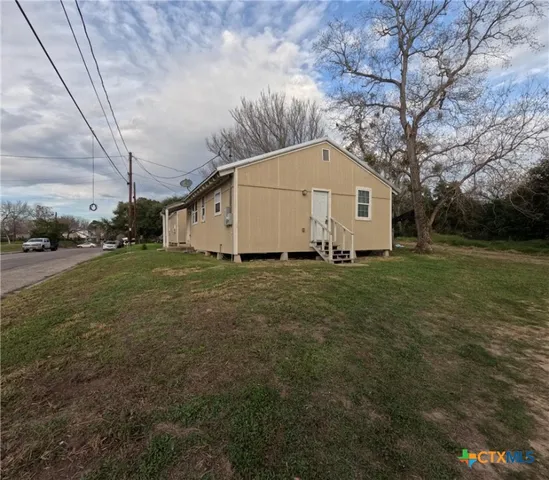 a view of a white house with a big yard with large trees
