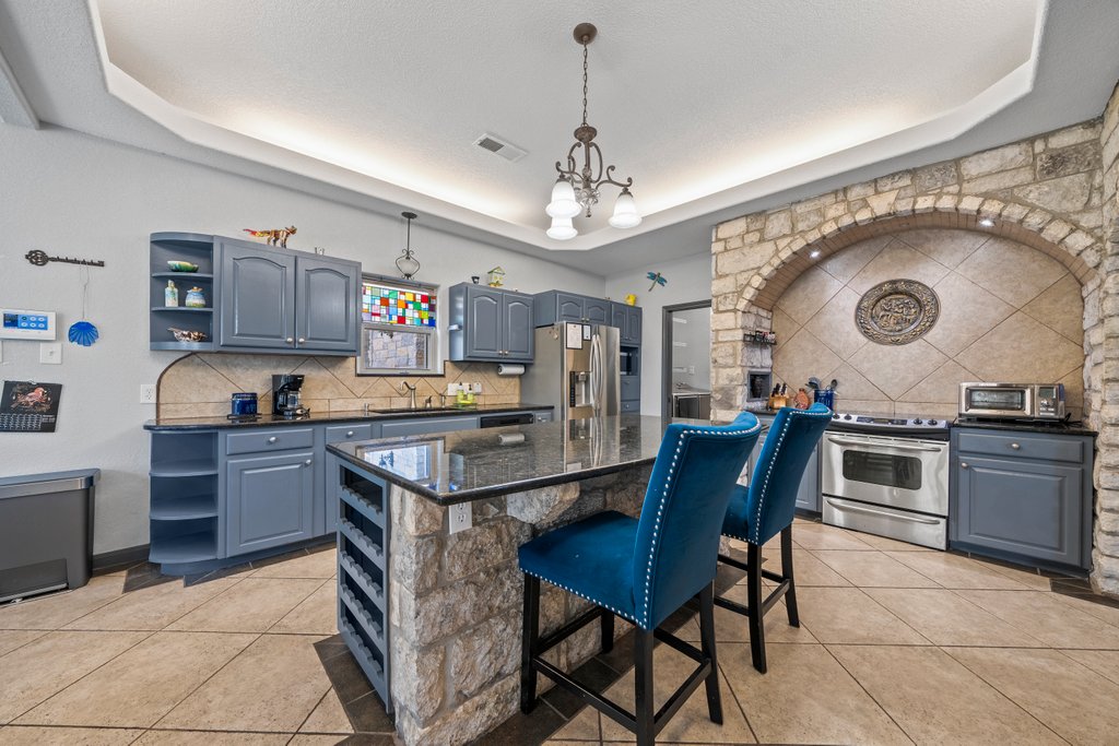 209 Lakeview Circle Spring Branch, TX 78070 - Photo 10 of 40 Kitchen with blue cabinets, stainless steel appliances, open shelves, tasteful backsplash, and a raised ceiling