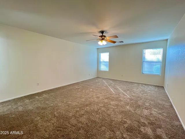 an empty room with windows and chandelier fan