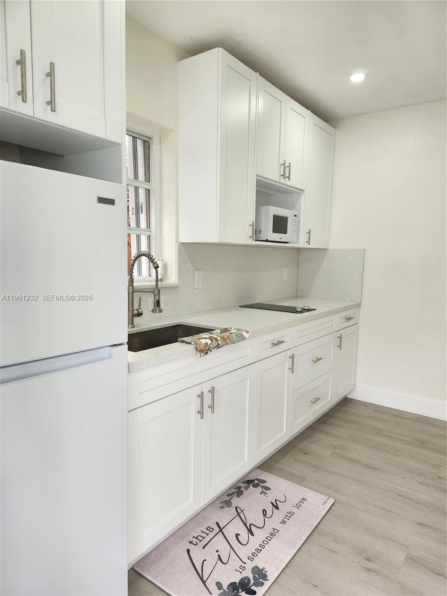 12460 Southwest 187th Terrace, Unit 1 Miami, FL 33177 - Photo 6 of 16 a kitchen with granite countertop a sink and a stove top oven