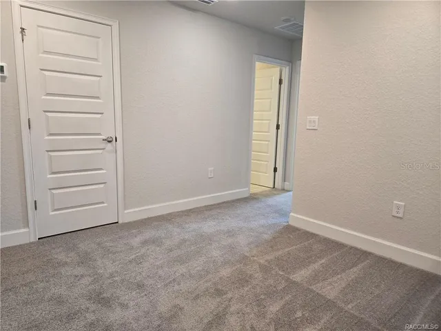 a view of an empty room with closet and a window