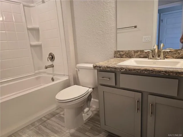 a bathroom with a granite countertop toilet a sink and a bathtub