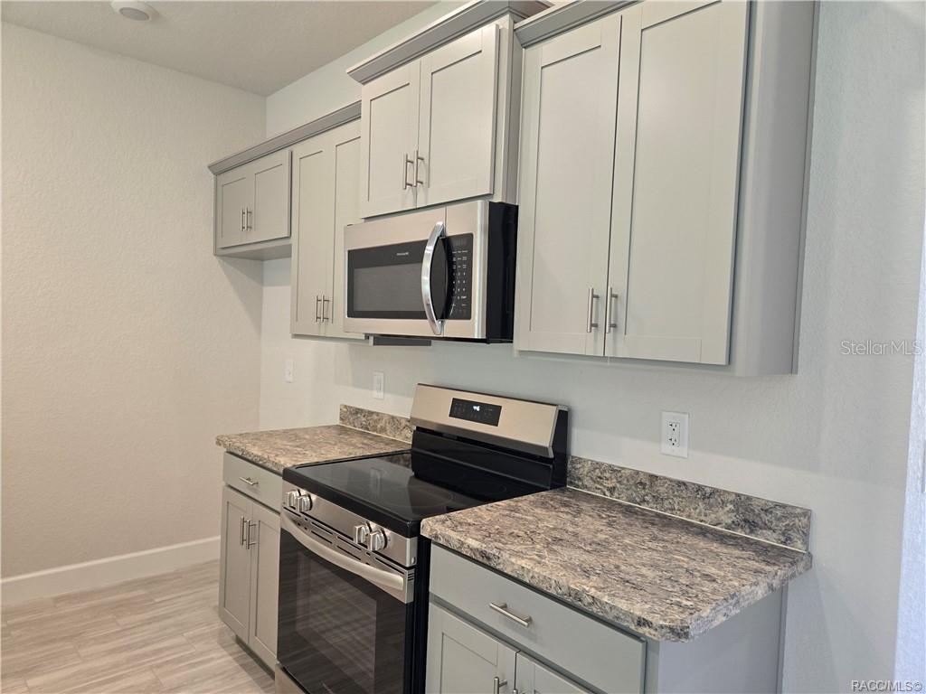 279 Bittern Loop Inverness, FL 34453 - Photo 3 of 30 a kitchen with stainless steel appliances granite countertop a sink stove and microwave