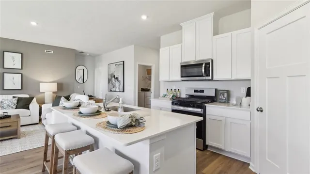 a kitchen with stainless steel appliances granite countertop a stove a sink a dining table and chairs