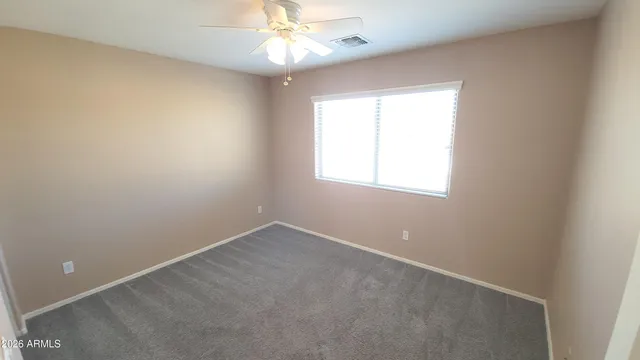 an empty room with a window and a fan