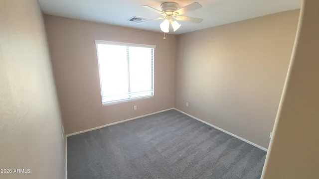 an empty room with a window and a fan