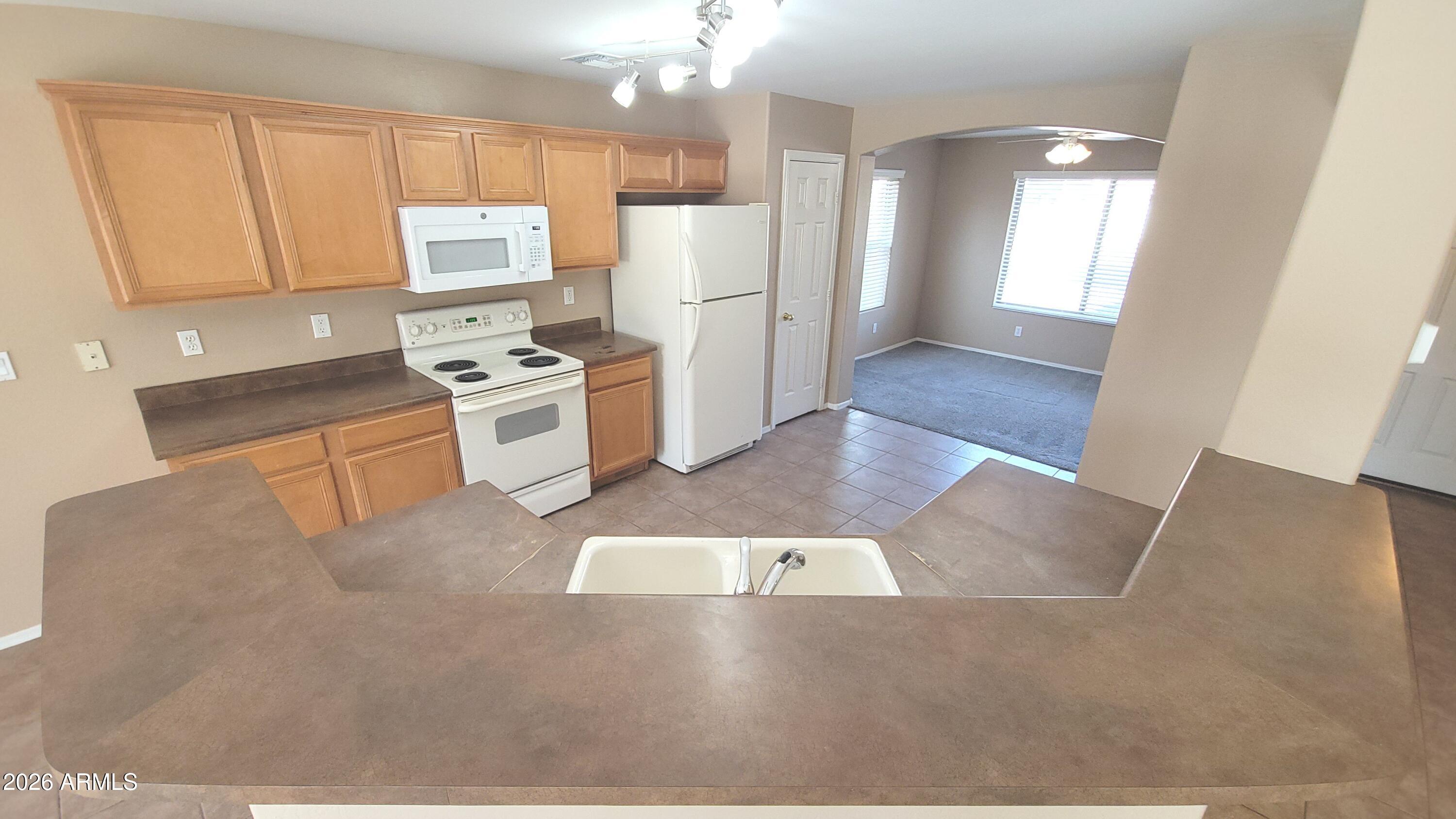 21821 East Via Del Rancho Queen Creek, AZ 85142 - Photo 10 of 35 a kitchen with a refrigerator a stove top oven and white cabinets
