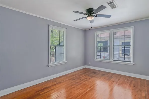 a view of an empty room with a window and wooden floor