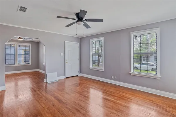 a view of an empty room with a window and wooden floor
