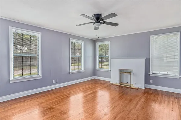 a view of an empty room with a window and wooden floor