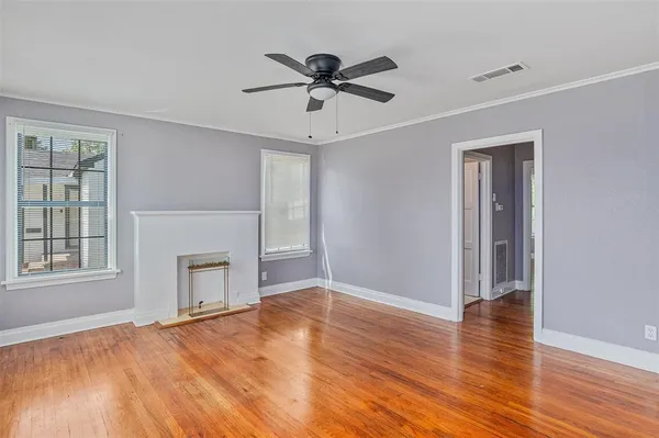 an empty room with wooden floor chandelier and windows