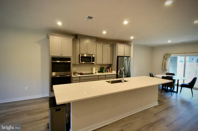 a kitchen with a sink a counter top space stainless steel appliances and wooden floor
