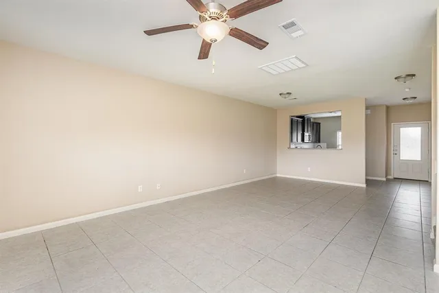 an empty room with chandelier fan and windows