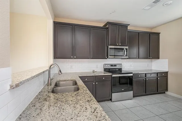 a kitchen with stainless steel appliances granite countertop a sink stove and microwave