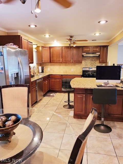 3741 Grosvenor Road Cleveland, OH 44118 - Photo 17 of 32 Kitchen with stainless steel appliances, backsplash, ceiling fan, a breakfast bar area, and light stone countertops