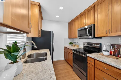 a kitchen with stainless steel appliances granite countertop a refrigerator a sink a stove and cabinets