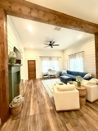 a living room with couches and kitchen view with wooden floor