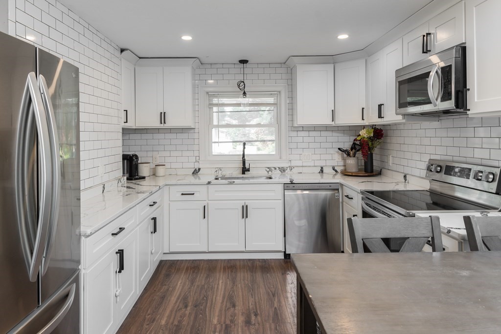 a kitchen with white cabinets stainless steel appliances a sink and a window