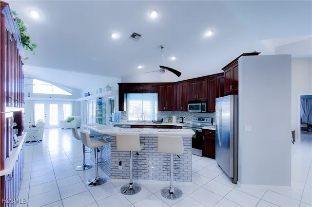 a kitchen with stainless steel appliances a refrigerator a stove a sink a dining table and chairs