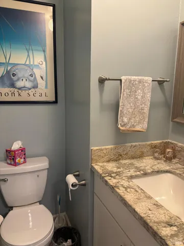 a bathroom with a granite countertop toilet and a sink
