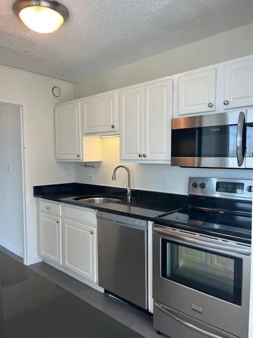 a kitchen with granite countertop a sink and a stove