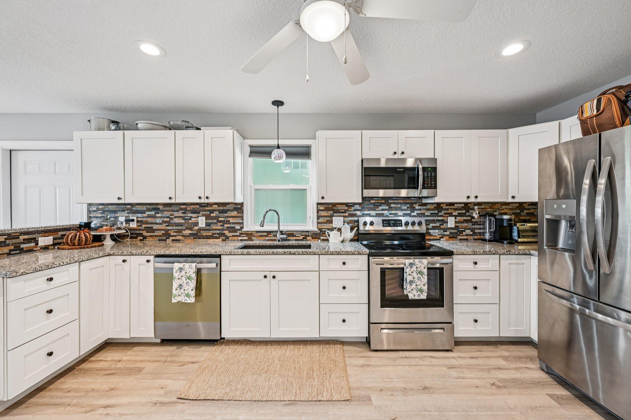 251 Southeast Paradise Place Stuart, FL 34997 - Photo 2 of 39 a kitchen with stainless steel appliances granite countertop a stove top oven a refrigerator a sink and dishwasher