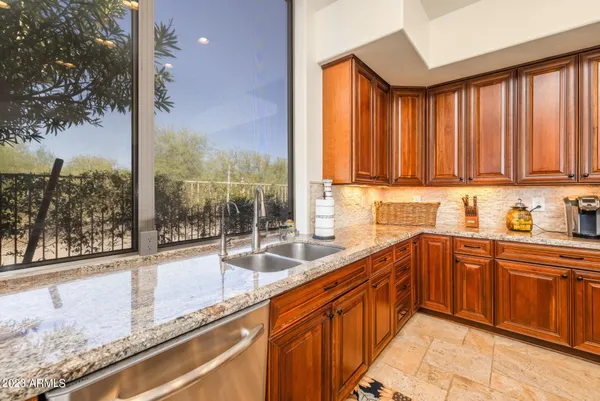 a kitchen with stainless steel appliances granite countertop a stove a sink dishwasher and a refrigerator with wooden cabinets