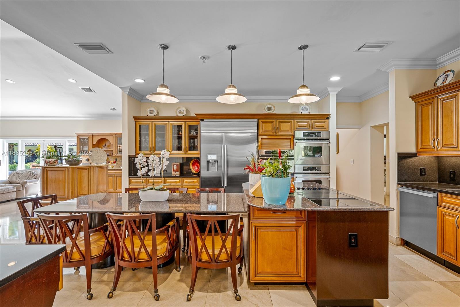 10735 Southwest 58th Avenue Pinecrest, FL 33156 - Photo 24 of 75 a kitchen with stainless steel appliances kitchen island granite countertop a table chairs and a refrigerator
