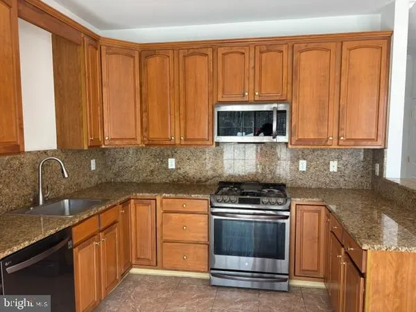 a kitchen with kitchen island granite countertop a sink cabinets and stainless steel appliances