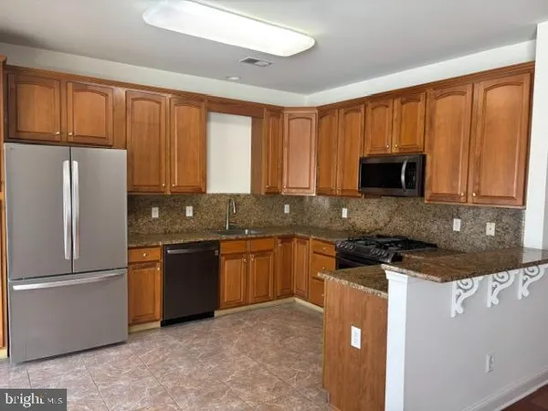 a kitchen with granite countertop wooden cabinets a refrigerator and a sink