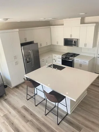 a kitchen with stainless steel appliances wooden floor dining table and chairs