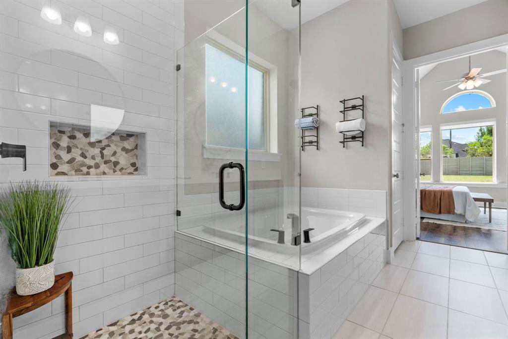 1821 Stonewall Road Argyle, TX 76226 - Photo 20 of 40 Glass-enclosed shower featuring white subway tile surround, a built-in pebble-tile niche, and a matching pebble-tile floor
