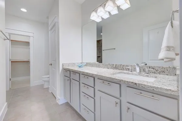 a bathroom with a granite countertop sink a toilet and a large mirror