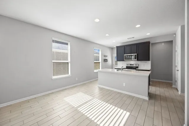 a large white kitchen with kitchen island a sink wooden floor and a refrigerator