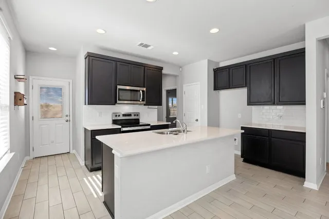 a kitchen with kitchen island granite countertop a stove top oven a sink dishwasher and a refrigerator with wooden floor