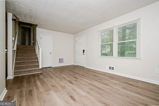 a view of an empty room with wooden floor and a window