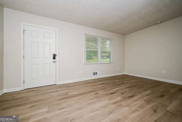 a view of an empty room with wooden floor and a window