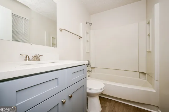 a bathroom with a granite countertop sink a toilet and shower