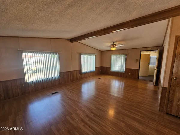 a view of empty room with wooden floor and fan