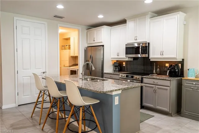 a kitchen with stainless steel appliances granite countertop a stove a sink a microwave a refrigerator and cabinets