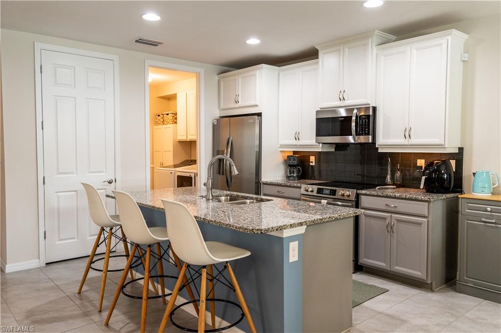 a kitchen with stainless steel appliances granite countertop a stove a sink a microwave a refrigerator and cabinets