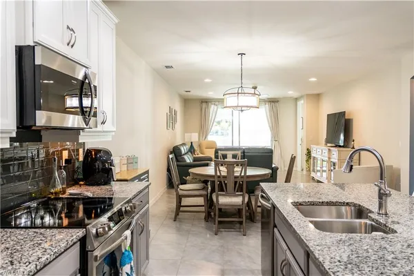 a kitchen with stainless steel appliances granite countertop a stove a sink a oven a dining table and chairs