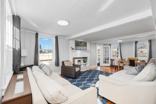 a living room with furniture large window and wooden floor