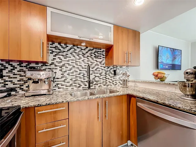 a kitchen with granite countertop stainless steel appliances a sink stove and cabinets