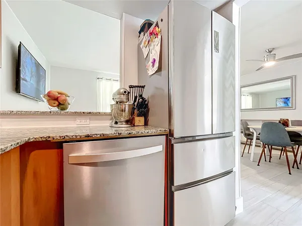 a kitchen with stainless steel appliances granite countertop a refrigerator a microwave a stove and a refrigerator with wooden floor