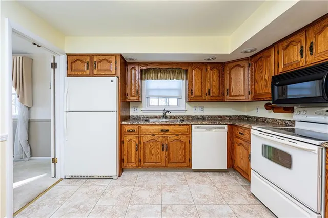 a kitchen with granite countertop a refrigerator and a stove top oven