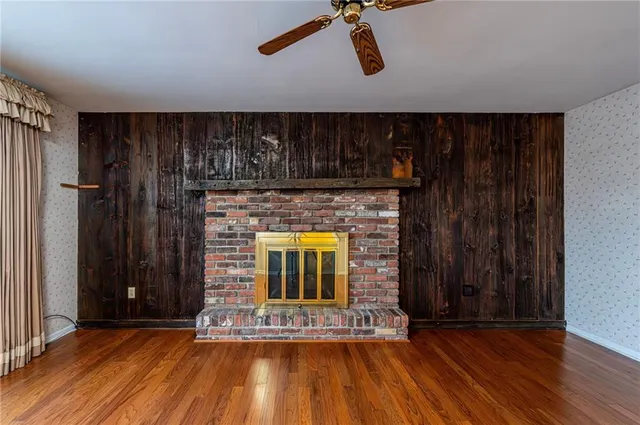 a view of an empty room with wooden floor and a fireplace
