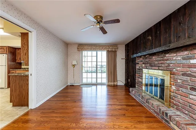a view of an empty room with wooden floor and a fireplace